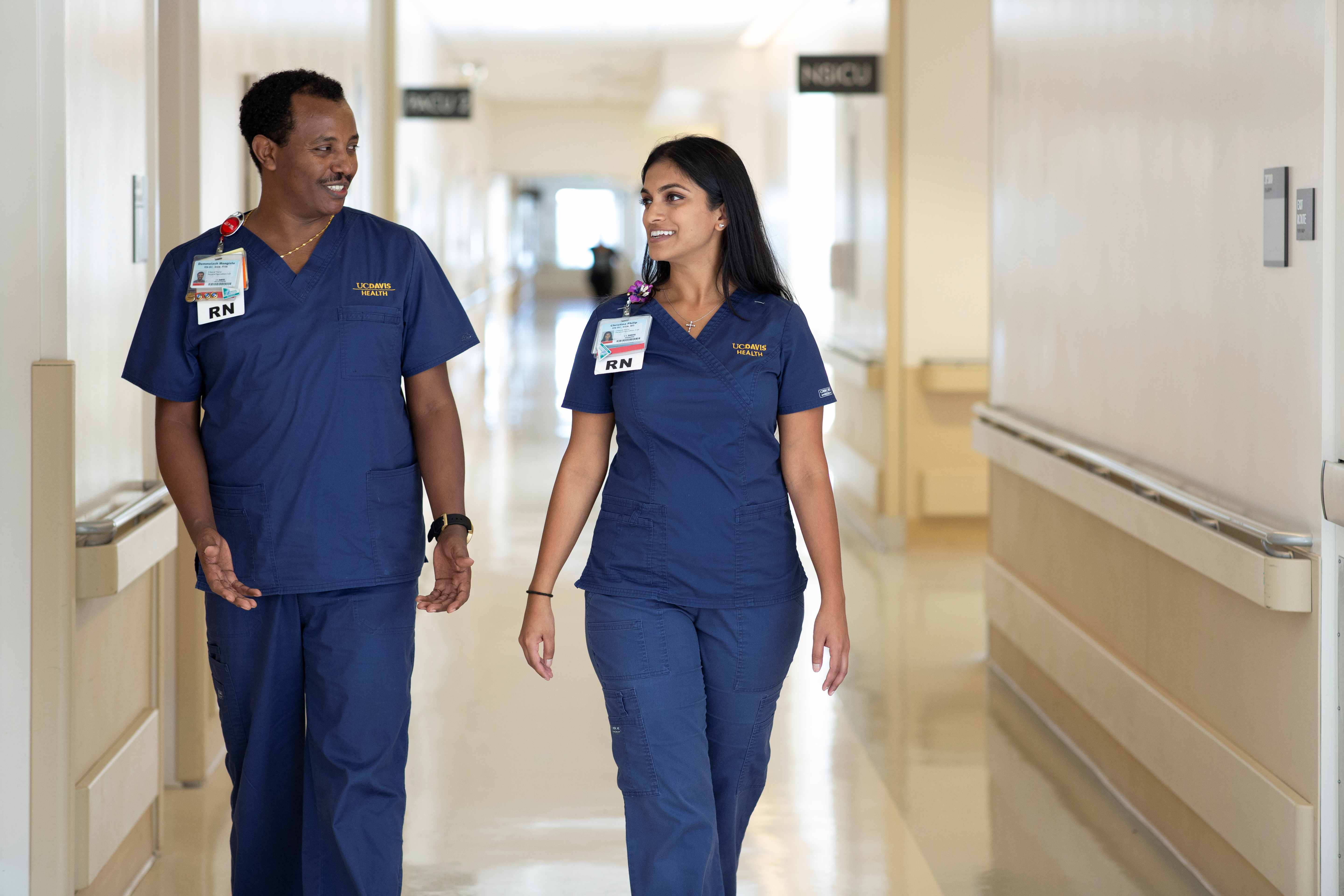 Two registered nurses walking side by side down the hallway