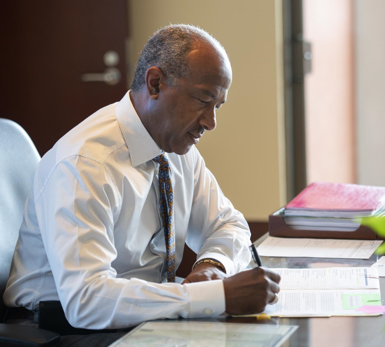 Chancellor Gary May writing something at office desk. 