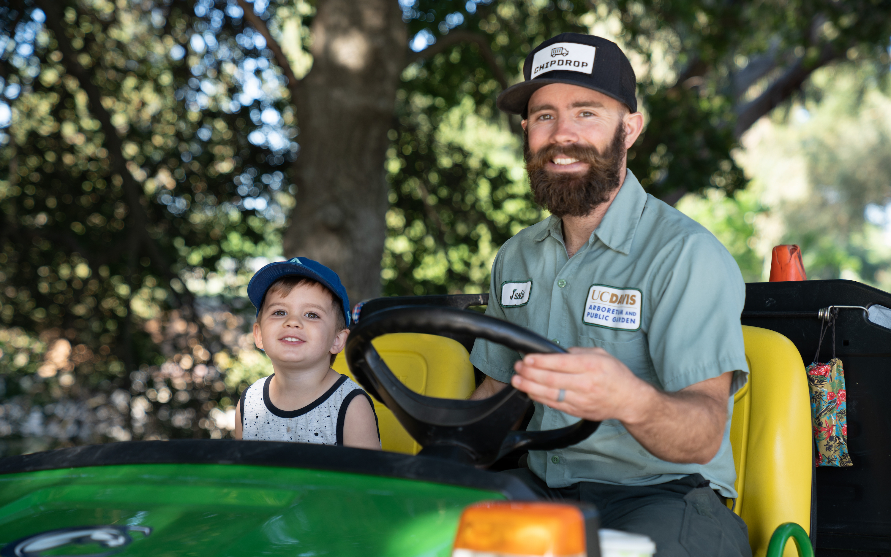 Employee driving tractor with young child beside him