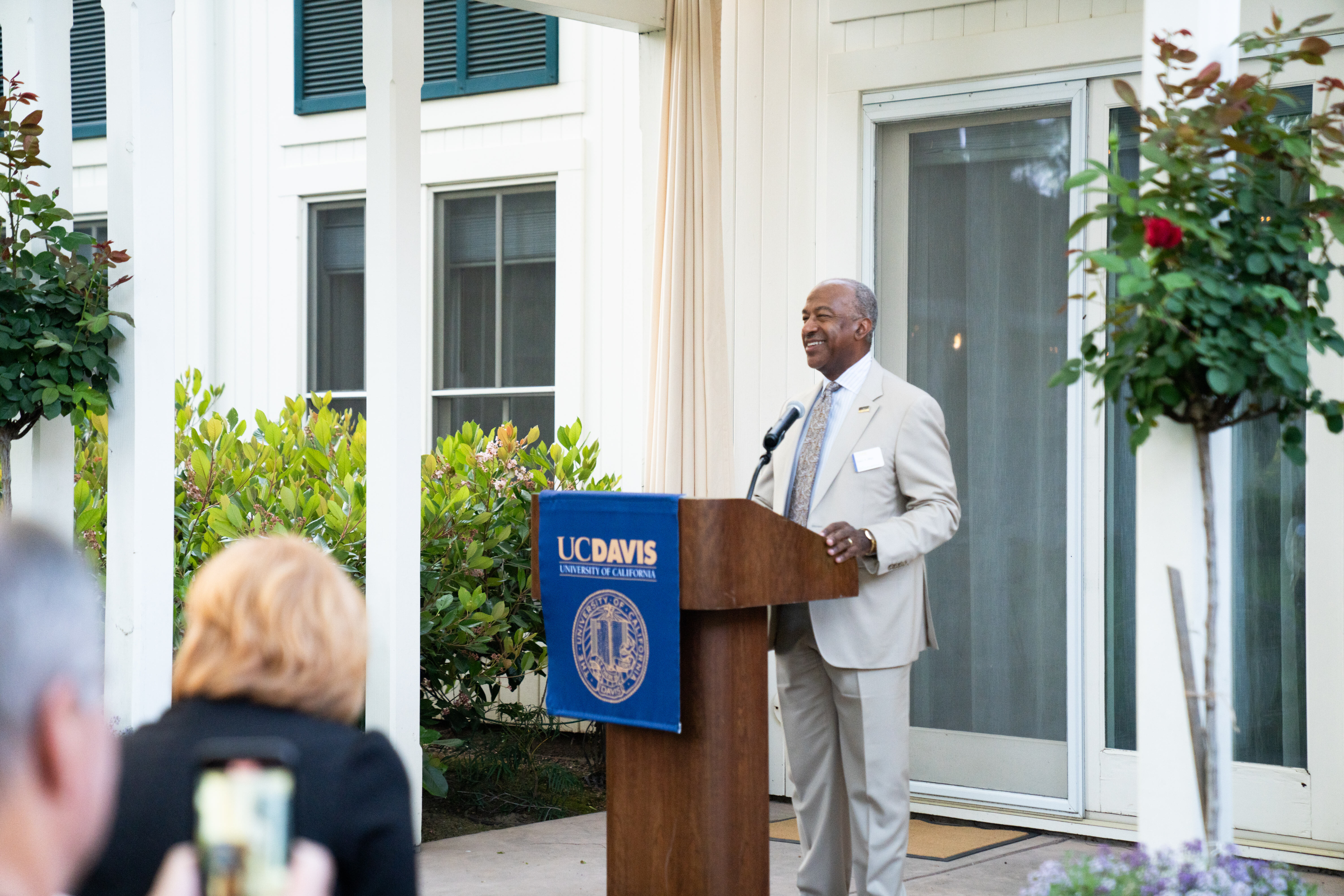 Chancellor May speaking at a lecturn to a group of seated people.