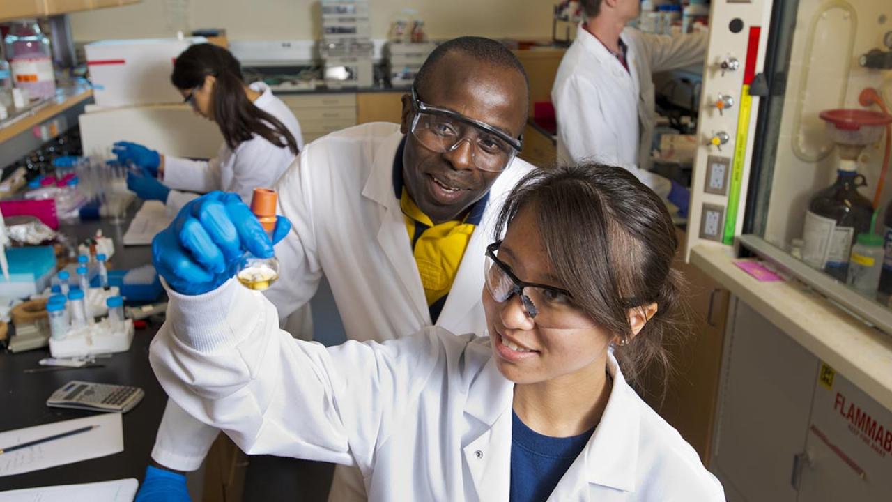 Researchers in laboratory looking at a glass vile