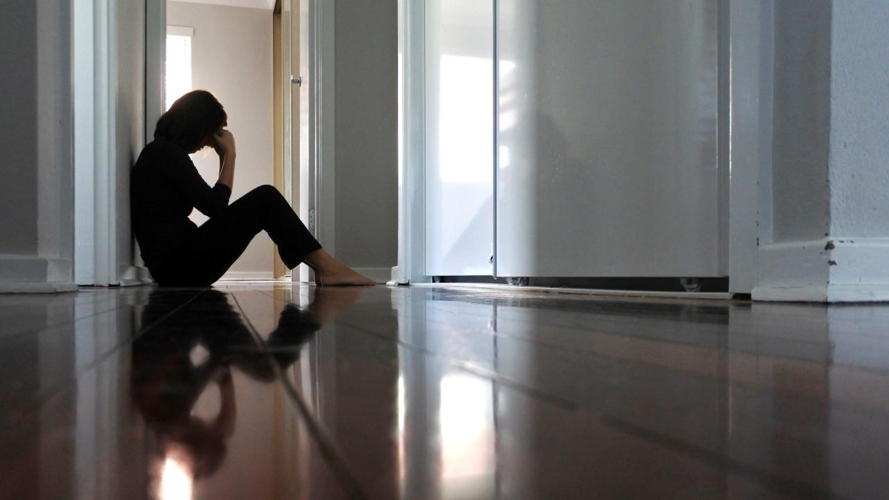 Woman is sitting on the floor alone.