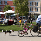 men and his daughter riding bikes with their dog running behind